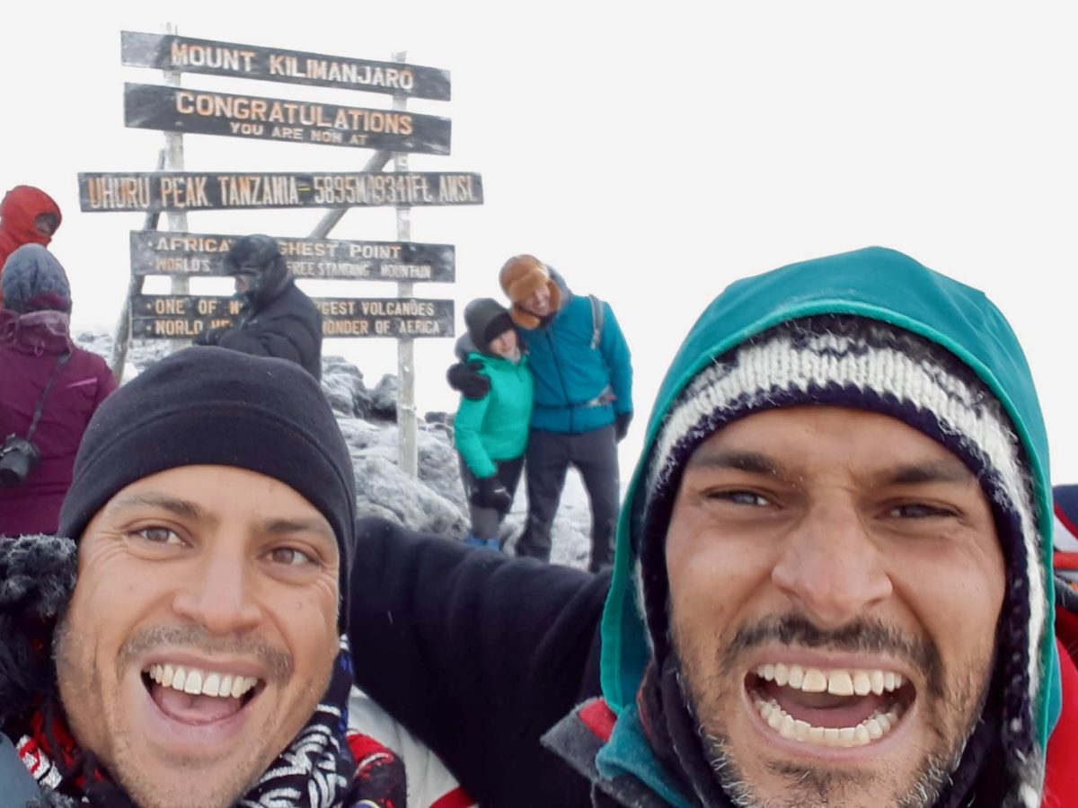 Two climbers in front of the Kilimanjaro summit sign
