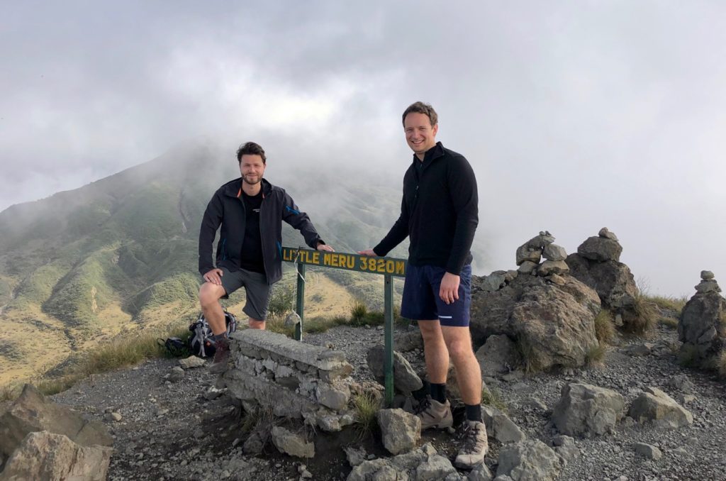 Deux alpinistes se tiennent devant l'enseigne du sommet de la Petite Meru